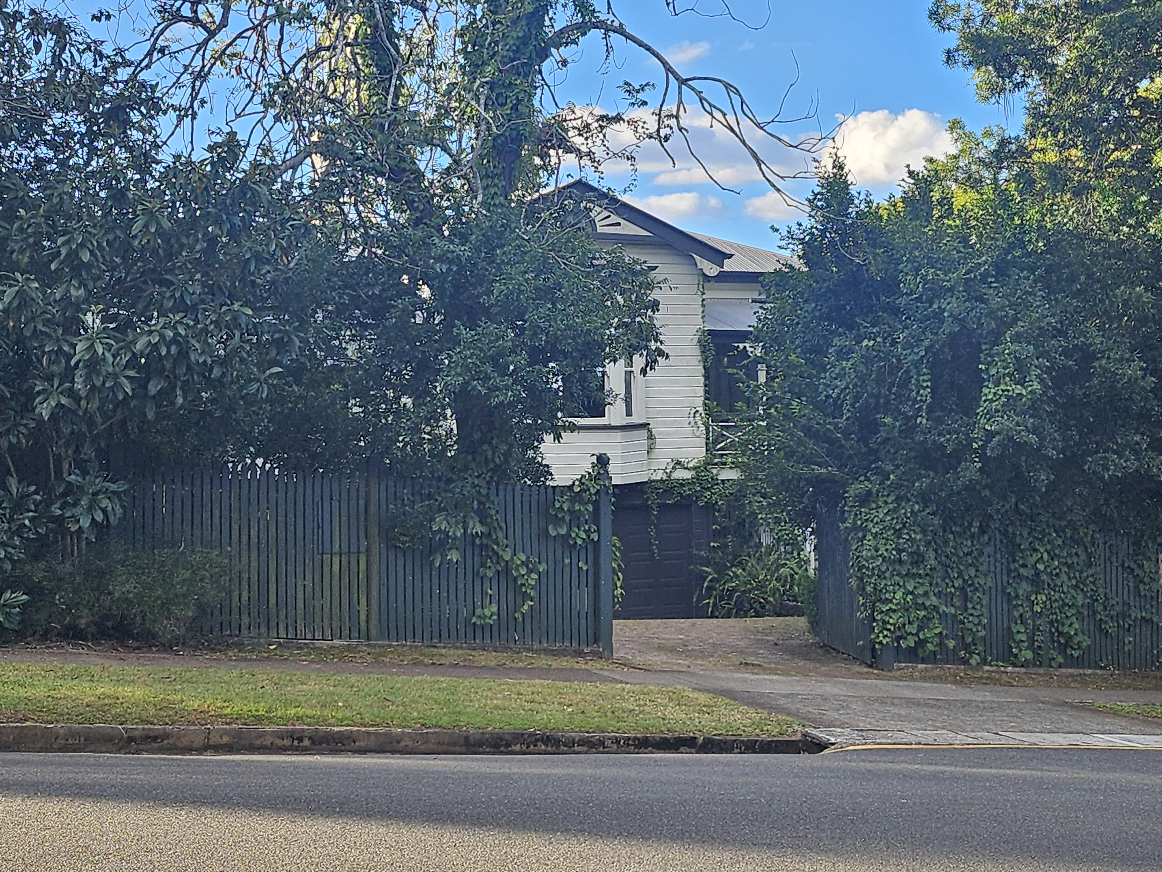 A house behind a high fence and vegetation