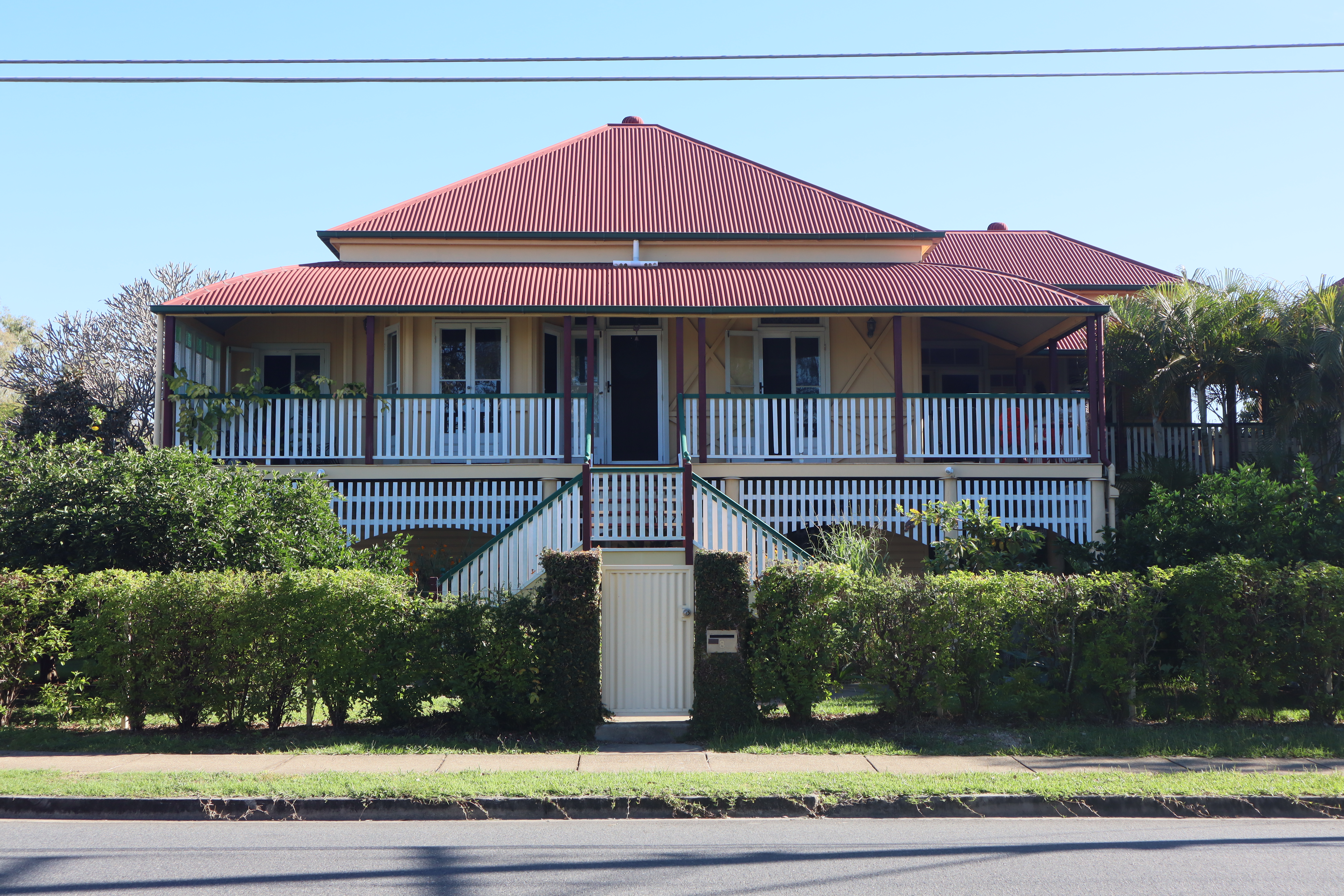 A house with a central staircase and hedges in front