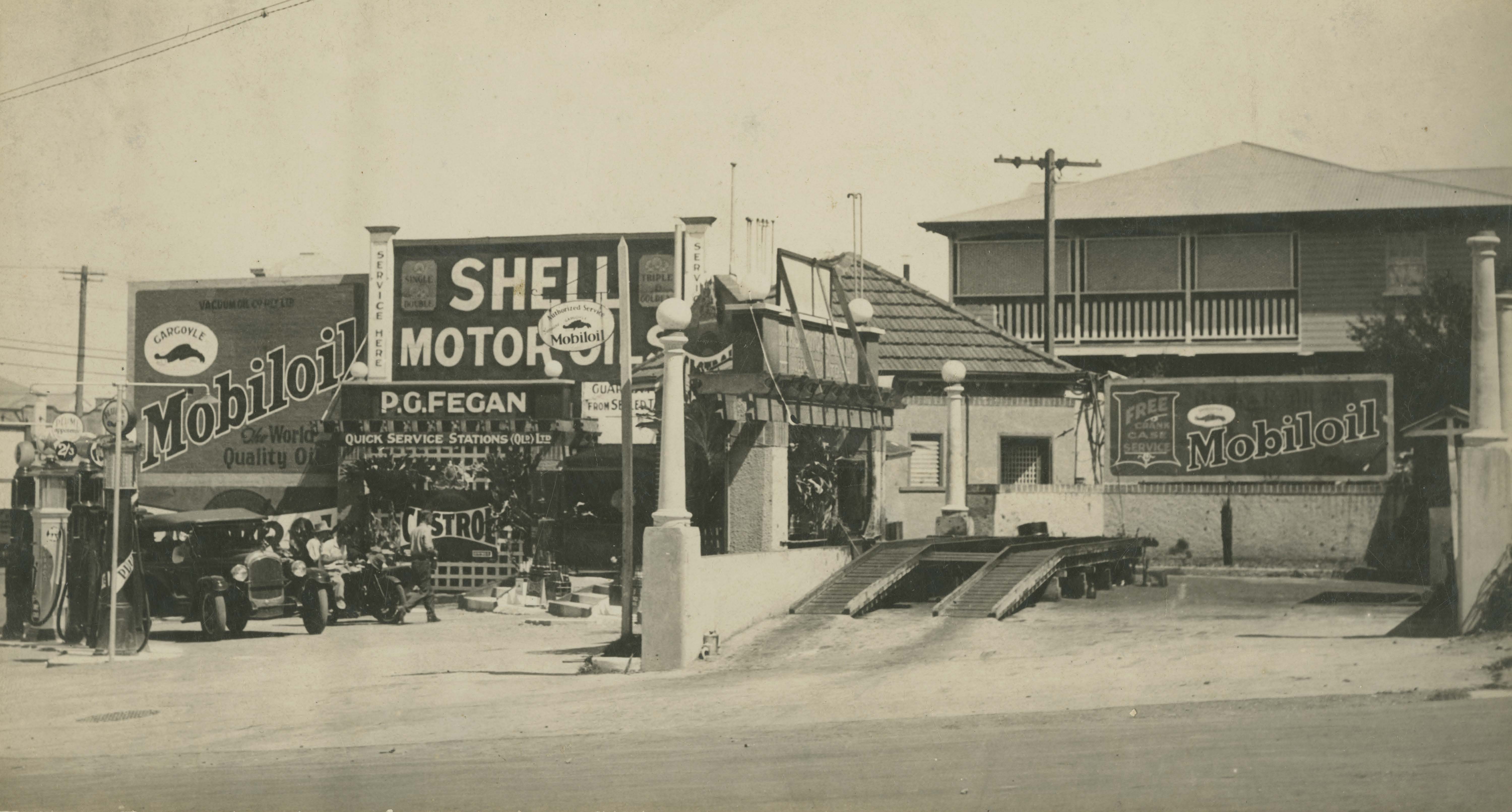 This is an image of ‘Pirie Grey Fegan's service station on Breakfast Creek Road in Newstead, Queensland, ca. 1935', viewed from the corner of Jordan Terrace & Breakfast Creek Road, Newstead, looking south.