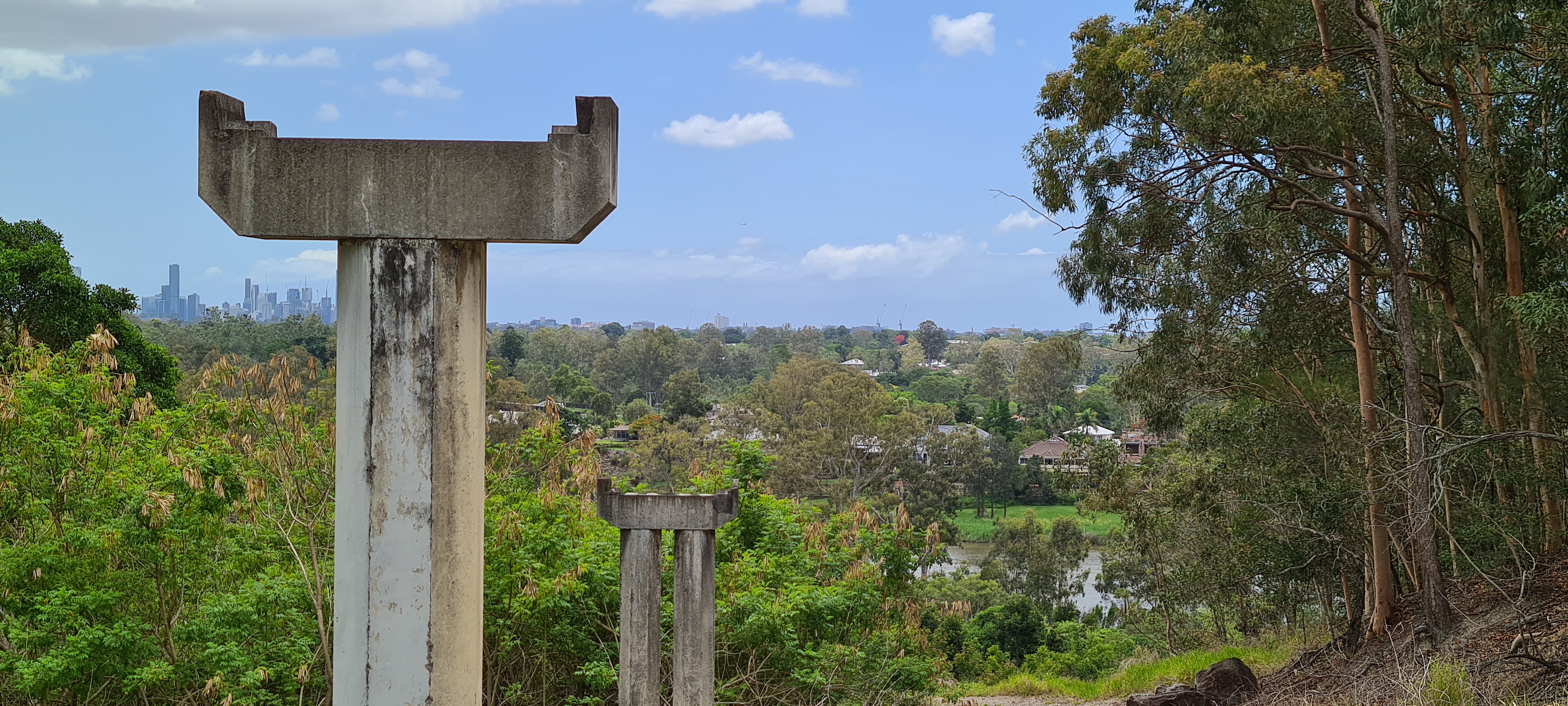 This is an image of concrete conveyor belt supports (remnants) - Queensland Cement and Lime Company conveyor belt remnants (Local heritage place) - viewed from parkland, end of Jennifer Street, Seventeen Mile Rocks (looking east) towards Brisbane River