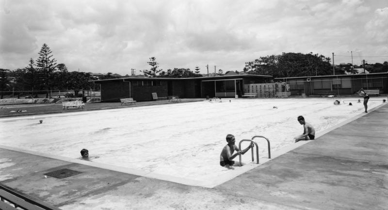 This is an image of 'Manly Swimming Pool and Amenities Block - Manly - 1964', 2 December 1964, showing a view of the swimming pool and amenities block from within the pool complex, looking south-west.